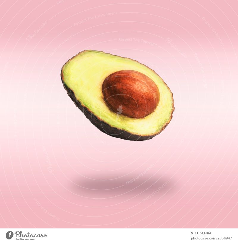 Fliegender halbe Avocado am rosa Hintergrund Lebensmittel Gemüse Ernährung Bioprodukte Vegetarische Ernährung Diät Lifestyle kaufen Design Gesunde Ernährung