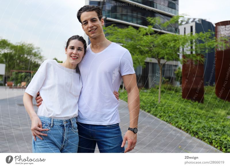 Schönes junges Paar, das sich umarmt, in die Kamera schaut und lächelt. Stil Freude Glück schön Sommer Flirten Frau Erwachsene Mann Straße T-Shirt Jeanshose