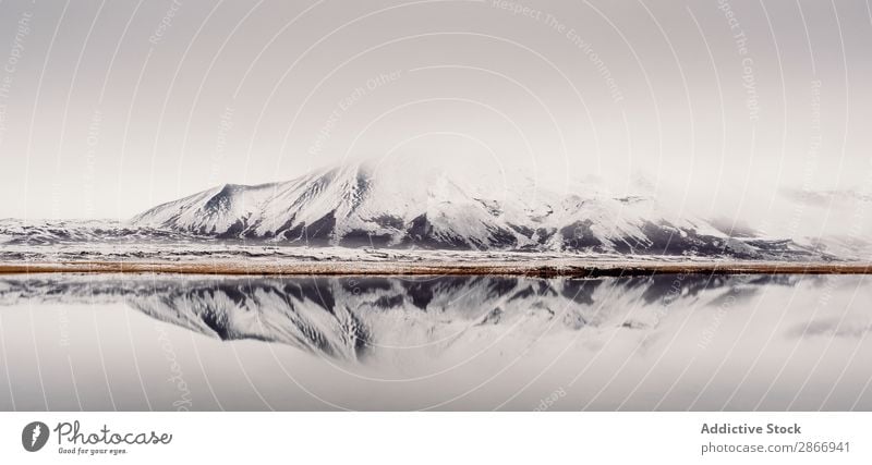 Wunderschöner See und Ufer mit Berg Schnee Hügel Küste malerisch Island Winter Stein Wasser regenarm Himmel Wolken Oberfläche Aussicht Natur