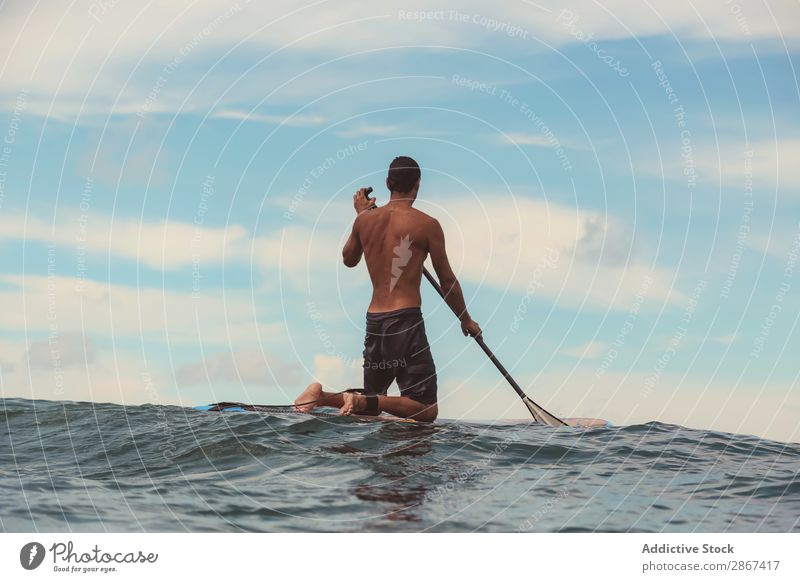 Mann mit Paddel auf dem Surfbrett winkend auf dem Wasser Oberfläche Sport Bali Indonesien Himmel Meer Himmel (Jenseits) blau Paddeln Rippeln Landschaft