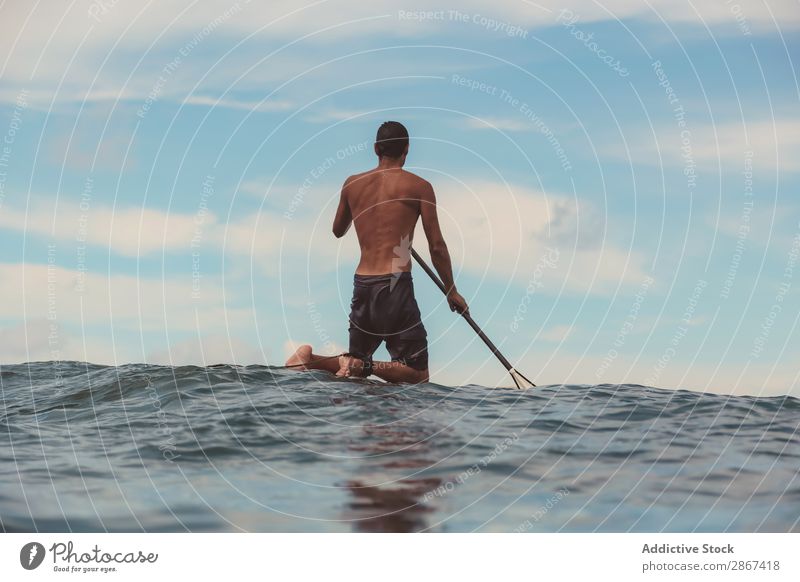 Mann mit Paddel auf dem Surfbrett winkend auf dem Wasser Oberfläche Sport Bali Indonesien Himmel Meer Himmel (Jenseits) blau Paddeln Rippeln Landschaft