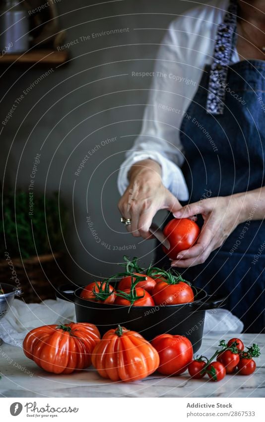 Frau, die Tomaten in einem Topf am Tisch schneidet. Schneiden Gemüse rot reif Messer frisch groß Lebensmittel Dame Mahlzeit rustikal Gesundheit kochen & garen