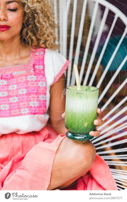 Attraktive elegante afroamerikanische Dame mit frischem Salat und Shake auf dem Stuhl. Frau schütteln Mexiko Afroamerikaner Glas schön trinken attraktiv schwarz