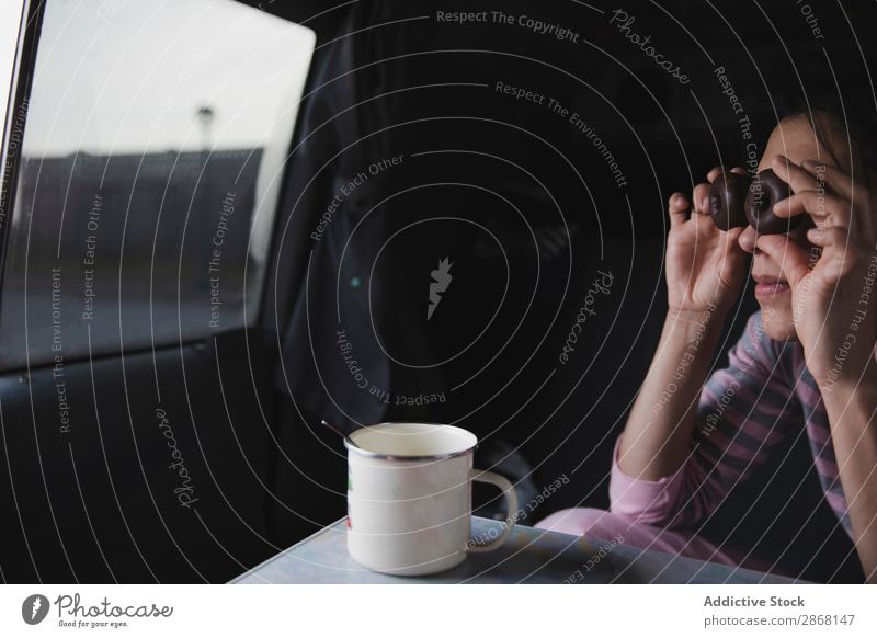 Frau mit Keksen in Augennähe im Auto sitzend mit Becher Biskuit PKW Tasse Blick Schokolade Plätzchen Löffel Tisch Jugendliche Snack Lebensmittel Dame