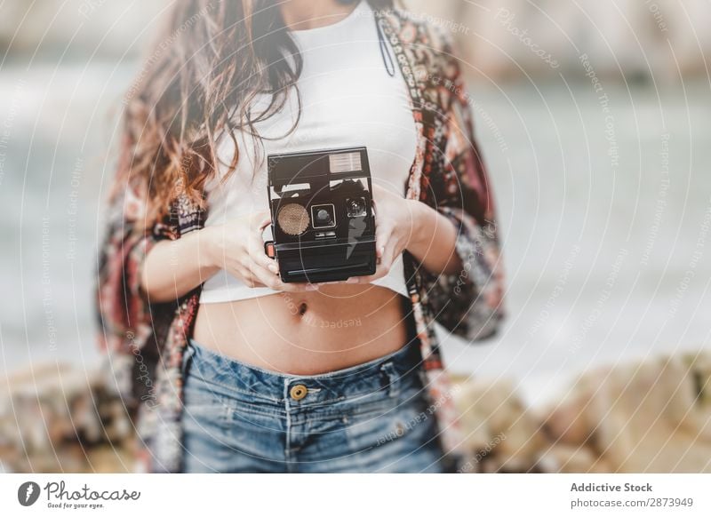 Dame mit Kamera an Land in der Nähe von Steinen und Wasser Frau Fotokamera Küste Meer Jugendliche Lifestyle laufen Felsen natürlich charmant Gerät Apparatur