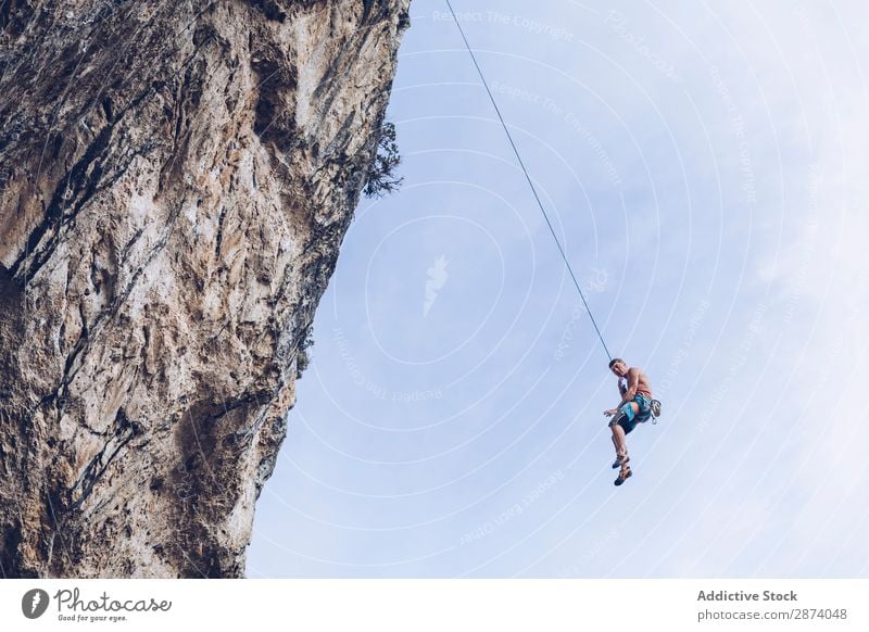 Anonymer Kletterer, der auf einer Klippe herumläuft. Aufsteiger erhängen Seil extrem Himmel blau Berge u. Gebirge Felsen Sport Herausforderung Aktion Erfolg