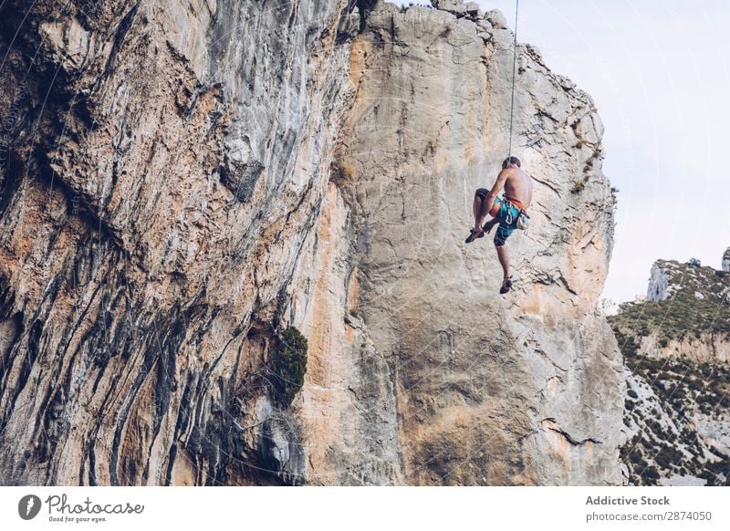 Anonymer Kletterer, der auf einer Klippe herumläuft. Aufsteiger erhängen Seil extrem Himmel blau Berge u. Gebirge Felsen Sport Herausforderung Aktion Erfolg