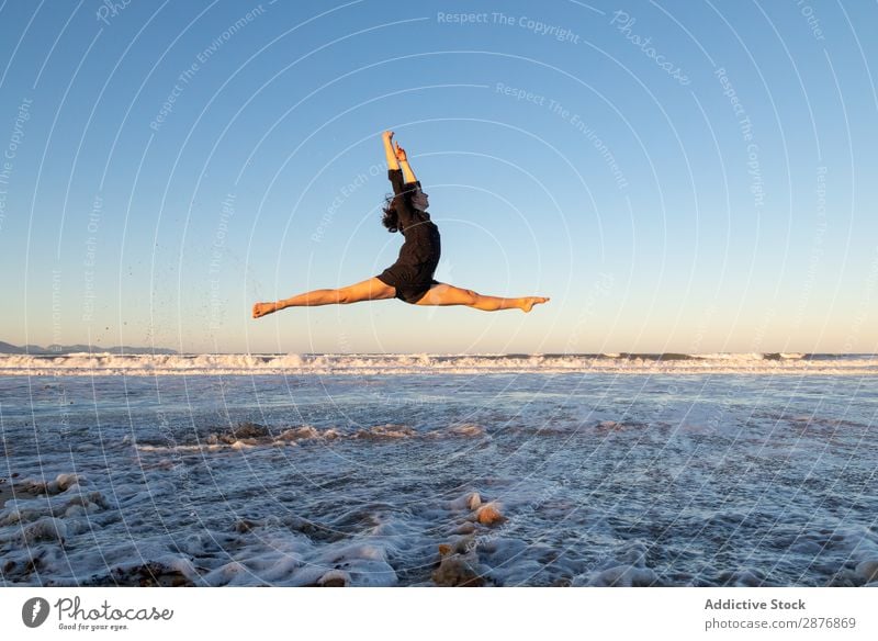 Frau, die am Ufer in der Nähe von Wasser springt. Tänzer Küste springen Meer Beine Seite Luft Himmel winkend Sand blau Jugendliche Balletttänzer Lifestyle