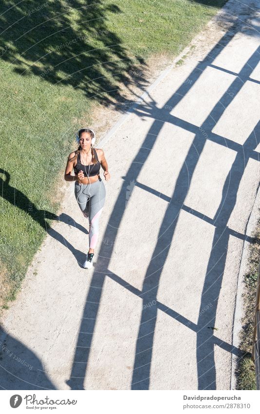 schöne junge Frau, die im Park joggt und im Freien Musik hört. Joggen rennen Fitness strecken üben Mädchen Jugendliche amerikanische Ethnie hören Kopfhörer