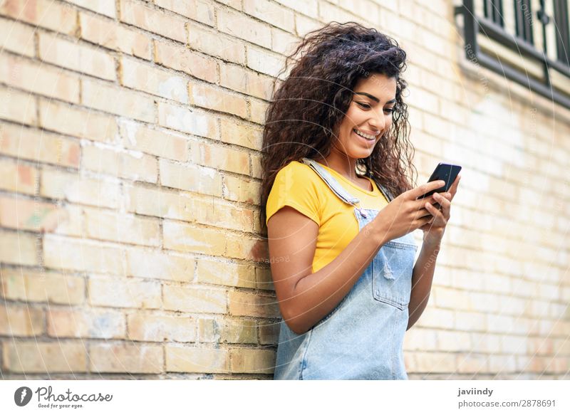 Junge nordafrikanische Frau beim SMSen mit ihrem Smartphone im Freien Lifestyle Stil Glück schön Haare & Frisuren Telefon PDA Technik & Technologie Mensch