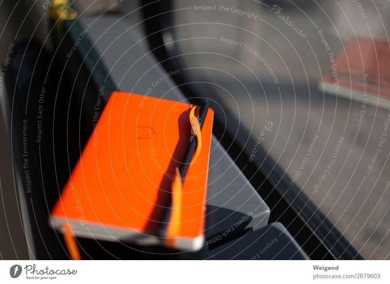 Notizbuch Schreibwaren Papier Zettel Schreibstift lesen schreiben orange Idee Konzept Bahnfahren Fenster Buch Literatur Farbfoto Textfreiraum rechts