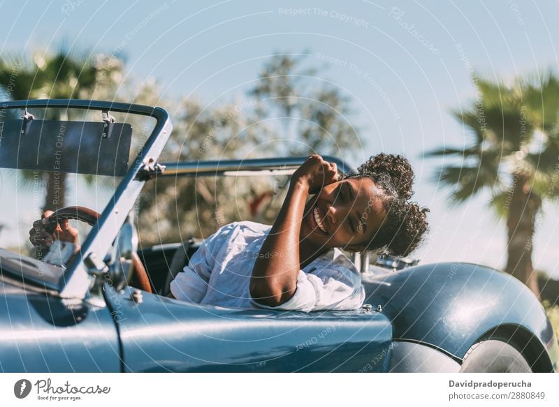 Schwarze Frau fährt ein Oldtimer-Cabriolet. PKW fahren urwüchsig Glück Straße schwarz Reichtum Wegsehen heiter Lächeln klassisch 60's schön Verkehr altehrwürdig