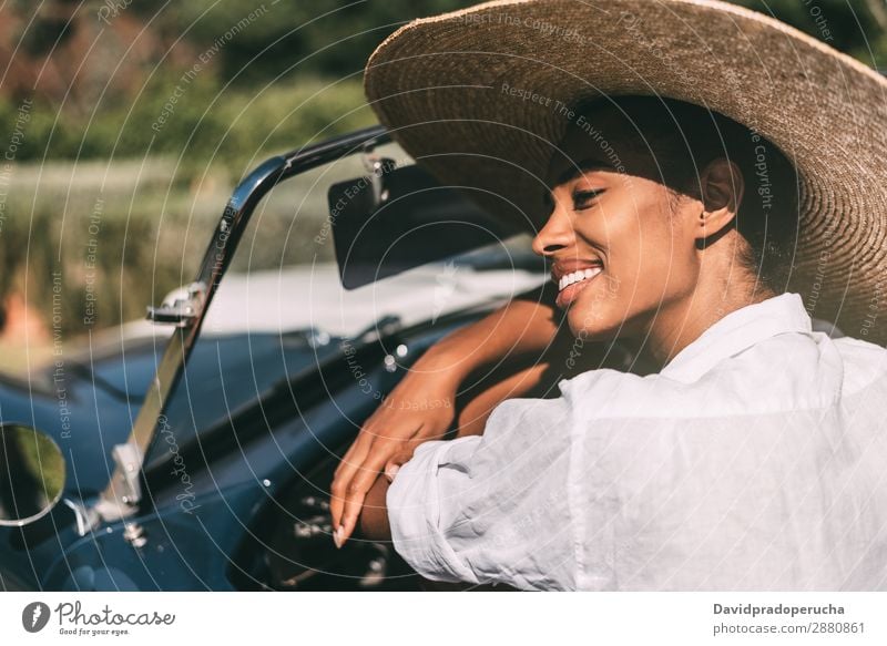 Schwarze Frau fährt ein Oldtimer-Cabriolet. PKW fahren urwüchsig Glück Straße schwarz Reichtum Wegsehen heiter Lächeln klassisch 60's schön Strohhut