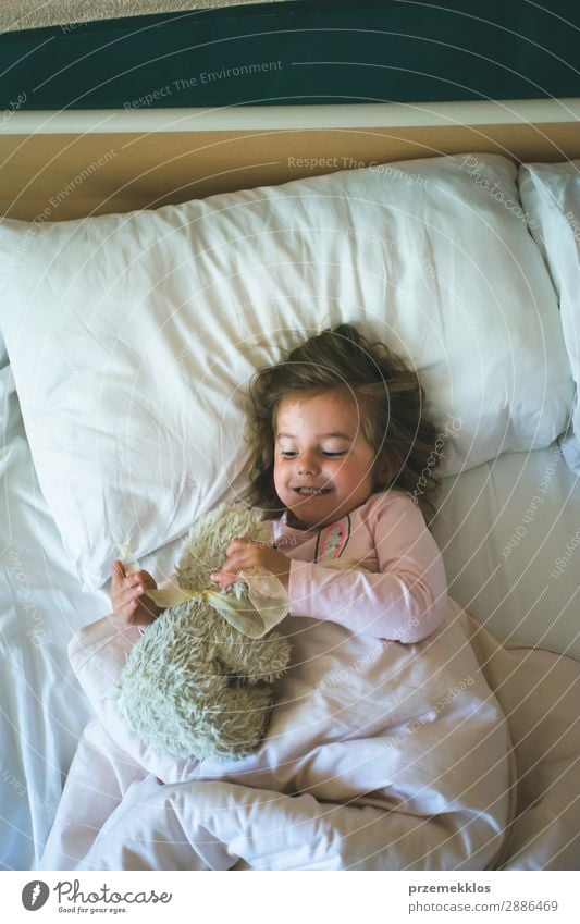 Kleines Mädchen, das morgens in einem Bett mit Teddybär liegt. Glück schön Spielen Kind Mensch Frau Erwachsene Spielzeug schlafen Fröhlichkeit klein niedlich