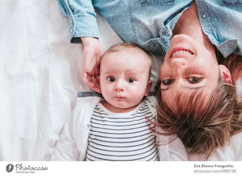 glückliche junge Mutter und ihr kleiner Junge liegen auf dem Bett und lächeln. Lifestyle Freude Glück Haut Lampe Schlafzimmer Kind Mensch maskulin feminin Baby