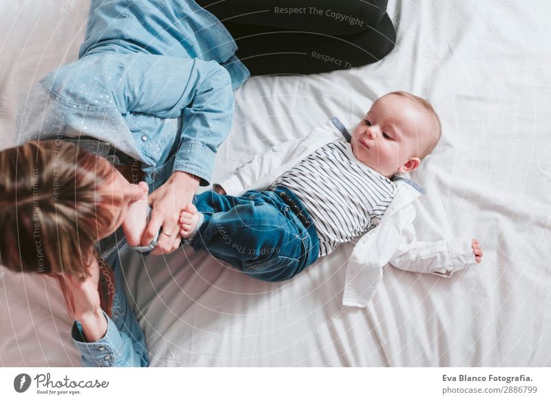 glückliche junge Mutter und ihr kleiner Junge liegen auf dem Bett und lächeln. Lifestyle Freude Glück Haut Lampe Schlafzimmer Kind Mensch feminin Baby Kleinkind