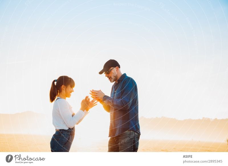 Vater und Tochter spielen am Strand bei Sonnenuntergang Handspiel. Freude Glück schön Spielen Kind Erwachsene Familie & Verwandtschaft Jeanshose Glatze Lächeln