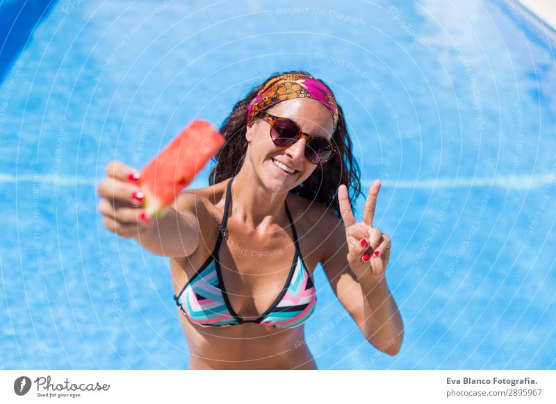 schöne junge Frau, die ein Stück Wassermelone hält. Frucht Diät Saft Freude Glück Haare & Frisuren Gesicht Maniküre Lippenstift Schwimmbad