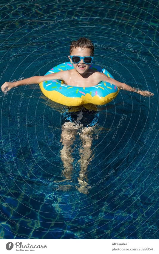 Ein kleiner glücklicher Junge, der tagsüber im Schwimmbad auf dem aufblasbaren Kreis spielt. Konzept der freundlichen Familie. Lifestyle Freude Glück Gesicht