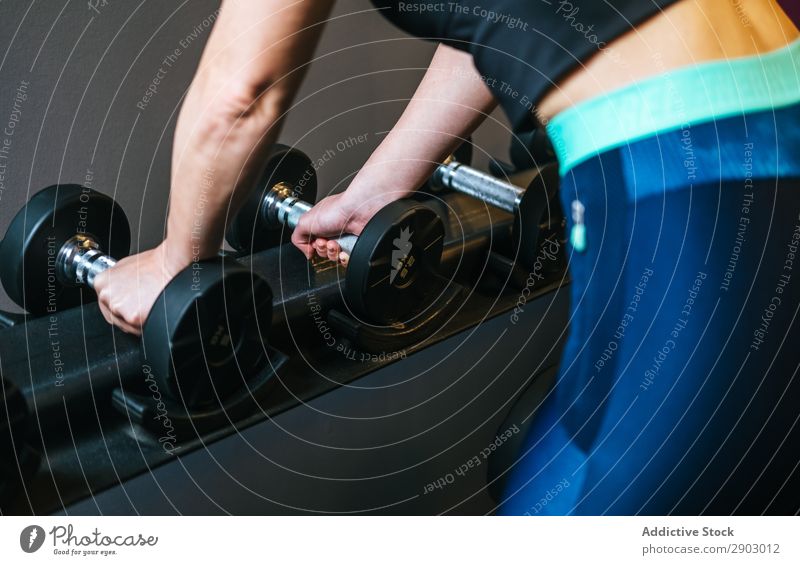 Frau mit Kurzhantel im Fitnessstudio nehmen Hantel Sporthalle Sportbekleidung Training Eisen üben Gerät sportlich Lifestyle Wohlgefühl Motivation Muskulatur