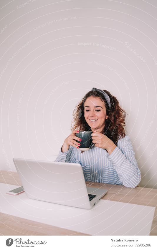 Brünette Frau benutzt ihren Computer, während sie einen Kaffee trinkt. Lifestyle Glück Schreibtisch Tisch Arbeit & Erwerbstätigkeit Büro Business Telefon