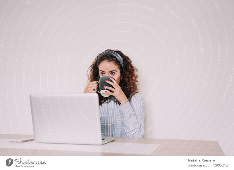 Brünette Frau benutzt ihren Computer, während sie einen Kaffee trinkt. Lifestyle Glück Schreibtisch Tisch Arbeit & Erwerbstätigkeit Büro Business Telefon