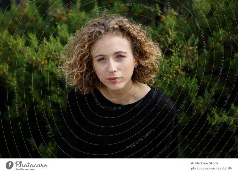 Junge Frau in der Nähe von trockenen Buschzweigen Sträucher Zweig attraktiv Pflanze Jugendliche Ast charmant regenarm Natur Lifestyle Sommer lockig