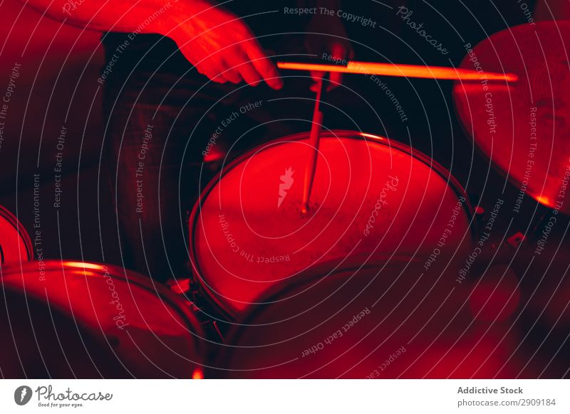 Anonymer Mann mit Trommelstöcken, die auf Trommeln in Rötung spielen. Trommelschlegel Hand Röte rot Licht Spielen Studioaufnahme Musik professionell Jugendliche