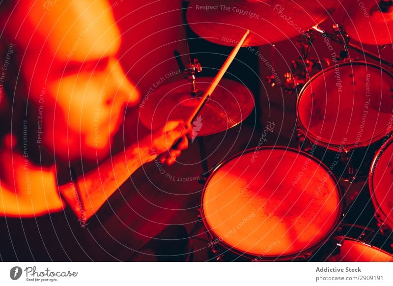 Mann mit Trommelstöcken, die auf Trommeln in Rötung spielen. Trommelschlegel Röte Spielen Studioaufnahme Musik professionell Jugendliche Schlagzeuger Gerät