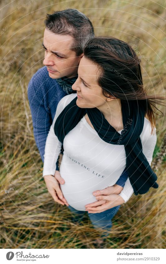 Schwangerschaft mit Partnerumarmung und Bauchhaltung Lifestyle Glück schön Mensch Frau Erwachsene Mann Mutter Paar Natur Landschaft Wind Gras Wiese Fluggerät