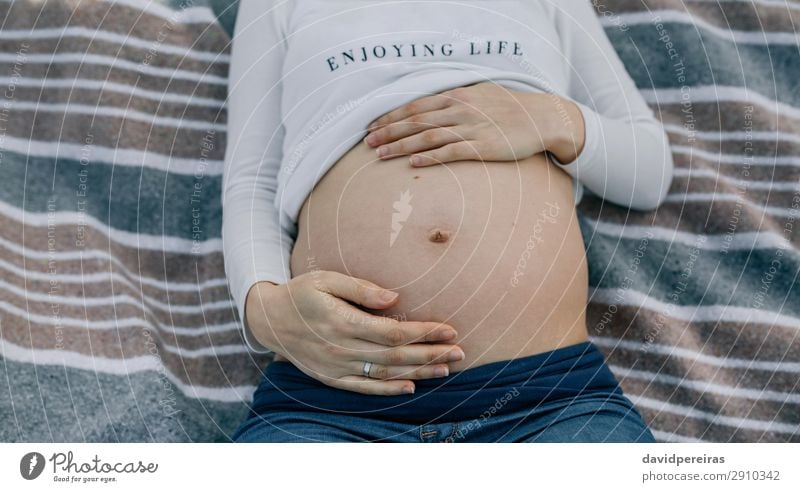 Schwangerer Bauch auf einer Decke liegend Lifestyle Leben Erholung Mensch Baby Frau Erwachsene Eltern Mutter Hand Fluggerät Ring berühren authentisch nackt