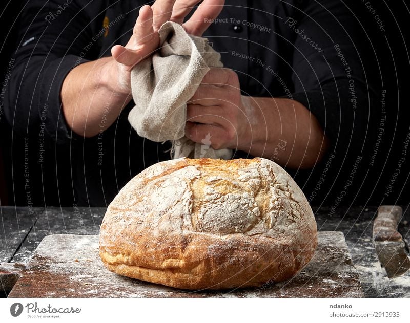 gebackenes Rundbrot auf einem Brett Teigwaren Backwaren Brot Ernährung Messer Tisch Küche Koch Mensch Hand Holz machen dunkel frisch braun schwarz Tradition