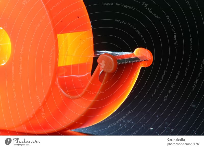 Kleberolle I Klebeband Langzeitbelichtung orange Schreibwaren Bürogerät Makroaufnahme Detailaufnahme Innenaufnahme Kunststoff Vor dunklem Hintergrund