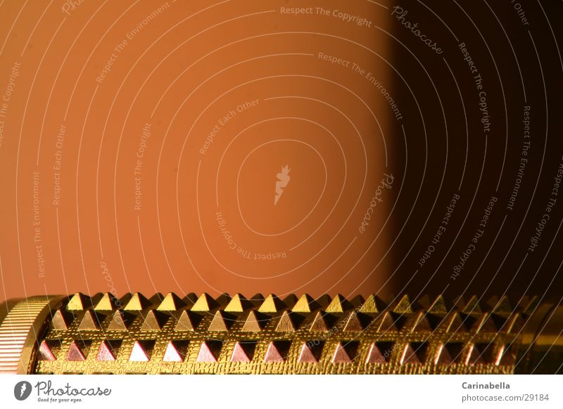 Massagerolle II Massagebürste glänzend obskur Massagestab Alluminium Pyramide Zacken Metall Kunstlicht Orange