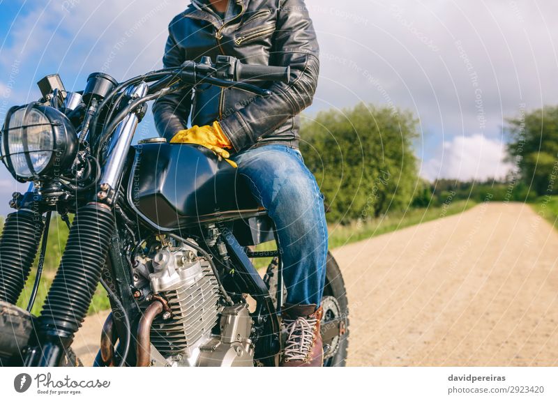 Mann auf einem Custom-Motorrad Lifestyle Mensch Erwachsene Natur Baum Verkehr Straße Wege & Pfade Fahrzeug Mode Jeanshose Handschuhe Stiefel warten authentisch