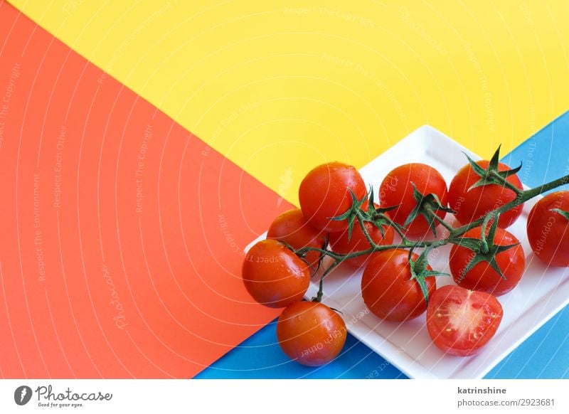 Kirschtomaten auf blauem, gelbem und korallenrotem Hintergrund Gemüse Vegetarische Ernährung Diät frisch hell oben Zutaten roh minimalistisch Entwurf leer