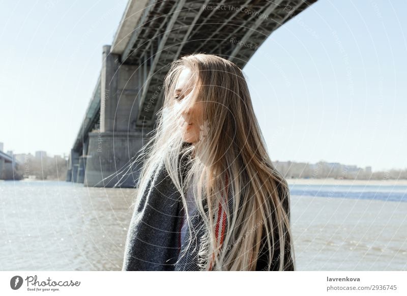 Porträt einer Frau an einem Strand mit fliegenden Haaren Ferien & Urlaub & Reisen blond Großstadt Brücke kalt Behaarung Wetter Schal Mantel Frühling Lifestyle