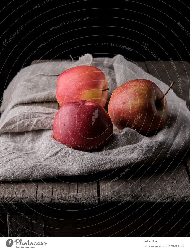 drei frische rote Äpfel lagen auf grauen Leinenservietten. Frucht Apfel Dessert Ernährung Vegetarische Ernährung Diät Tisch Natur Pflanze Herbst Holz natürlich