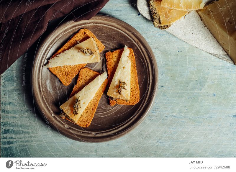 Halbgereifter Käse Rosmarin auf geröstetem Brot geschnitten Lebensmittel Bioprodukte Vegetarische Ernährung Diät Gastronomie alt dunkel frisch lecker natürlich