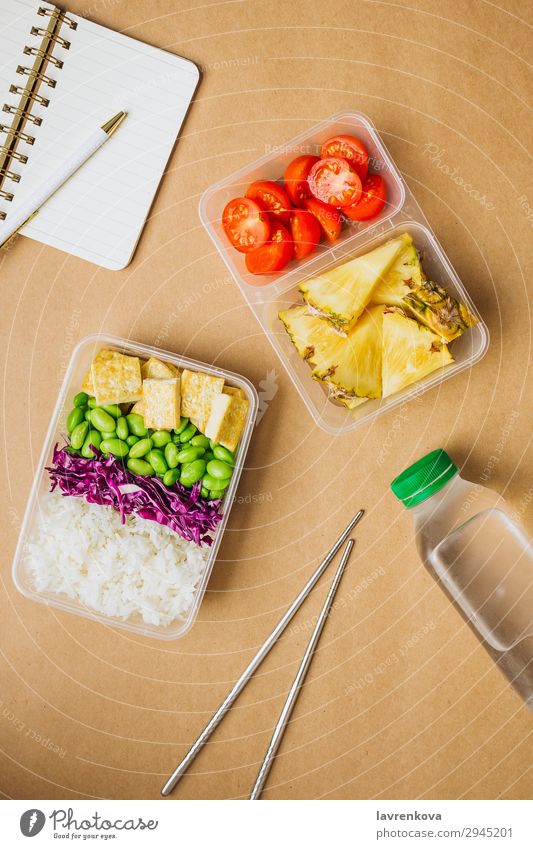 Gesunde vegane Bento-Box im asiatischen Stil Schreibstift Notizbuch Hobel Flasche Wasser Tomate geschnitten Ananas Rotkohl geschmackvoll Essen zubereiten