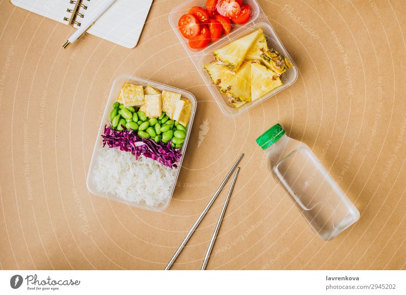 Gesunde vegane Bento-Box im asiatischen Stil Schreibstift Notizbuch Hobel Flasche Wasser flache Verlegung Tomate geschnitten Ananas Rotkohl geschmackvoll