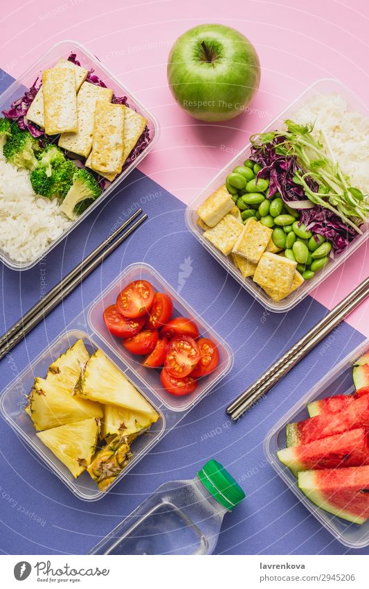 Zwei gesunde vegane Lunch-Bento-Boxen im asiatischen Stil Flasche Anklopfen Apfel Flachlegung Asiatische Küche Asiatische Reistafel Brokkoli Tomate Container