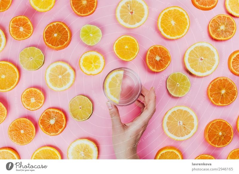 Frauenhand mit Zitronenwasser und geschnittenen Zitrusfrüchten rosa flache Verlegung freches Wasser Halt Hand Limone rund Diät Vegetarische Ernährung