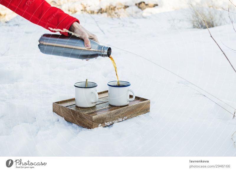 Männliche Hand, die heißen Kaffee oder Tee in eine Email-Tasse gießt. Getränk Kasten kalt Emaille Frost gefroren wandern Halt Mann Metall Becher Natur