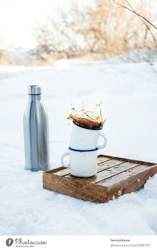 Zwei emaillierte Tassen mit spritzendem Kaffee im Freien. Ferien & Urlaub & Reisen Becher Emaille platschen Herbst Außenaufnahme Tablett Kasten wandern Picknick