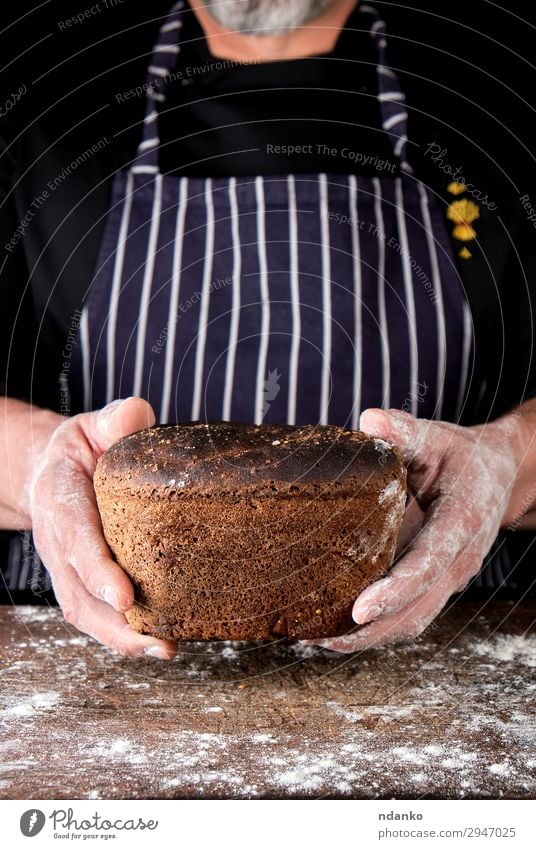 Hände halten braun gebackenes Roggenbrot. Brot Ernährung Essen Mittagessen Abendessen Diät Tisch Küche Mann Erwachsene Hand Holz dunkel frisch lecker natürlich