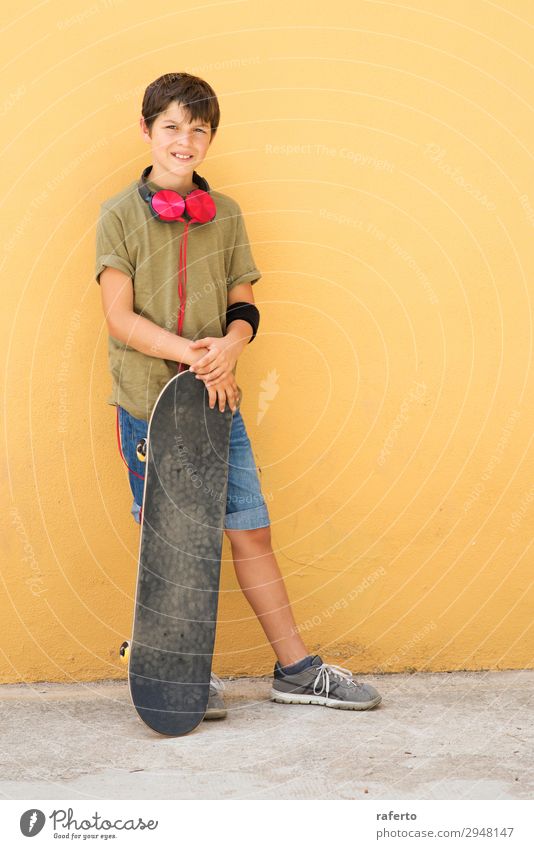 Kleiner Junge, der sich an eine gelbe Wand lehnt und Kopfhörer am Hals hat. Stil Musik Kind Telefon PDA Mensch maskulin Junger Mann Jugendliche Erwachsene 1