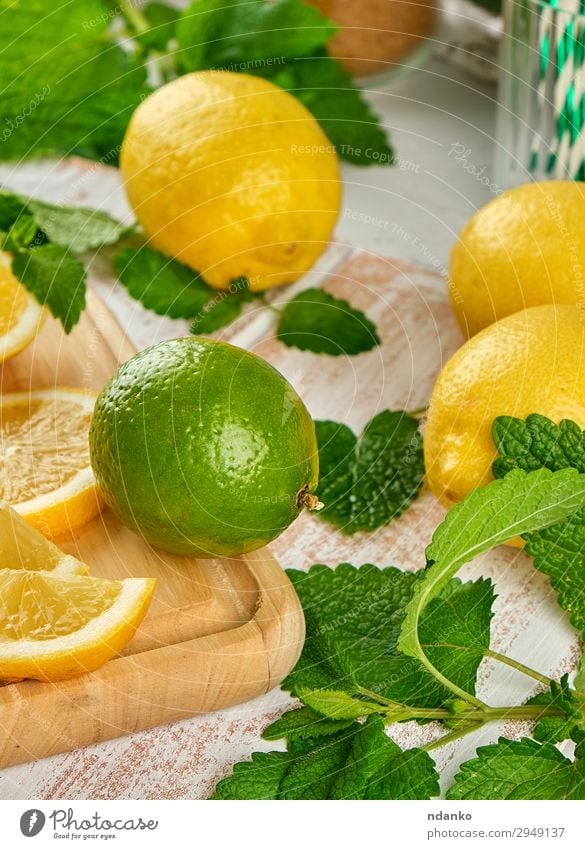 reife gelbe Zitronen und Limetten, minzgrün Frucht Erfrischungsgetränk Limonade Saft Tisch Blatt Holz oben saftig braun weiß Haufen Zitrusfrüchte Cocktail