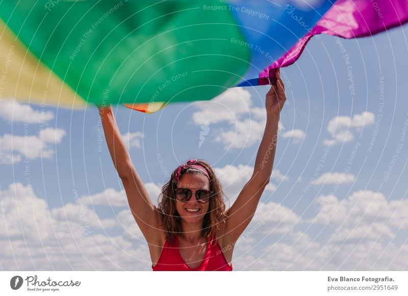 Frau hält die Gay Rainbow Flag über dem blauen Himmel im Freien. Lifestyle Freude Glück Freizeit & Hobby Freiheit Sommer Sonne Hochzeit Mensch feminin