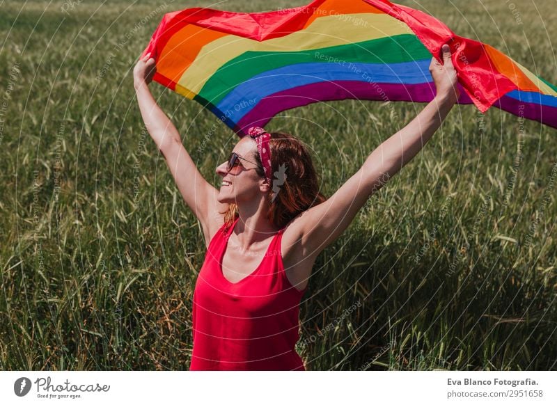 Frau hält die Gay Rainbow Flag auf einer grünen Wiese im Freien. Lifestyle Freude Glück Freiheit Sommer Sonne Hochzeit Mensch feminin Homosexualität Junge Frau